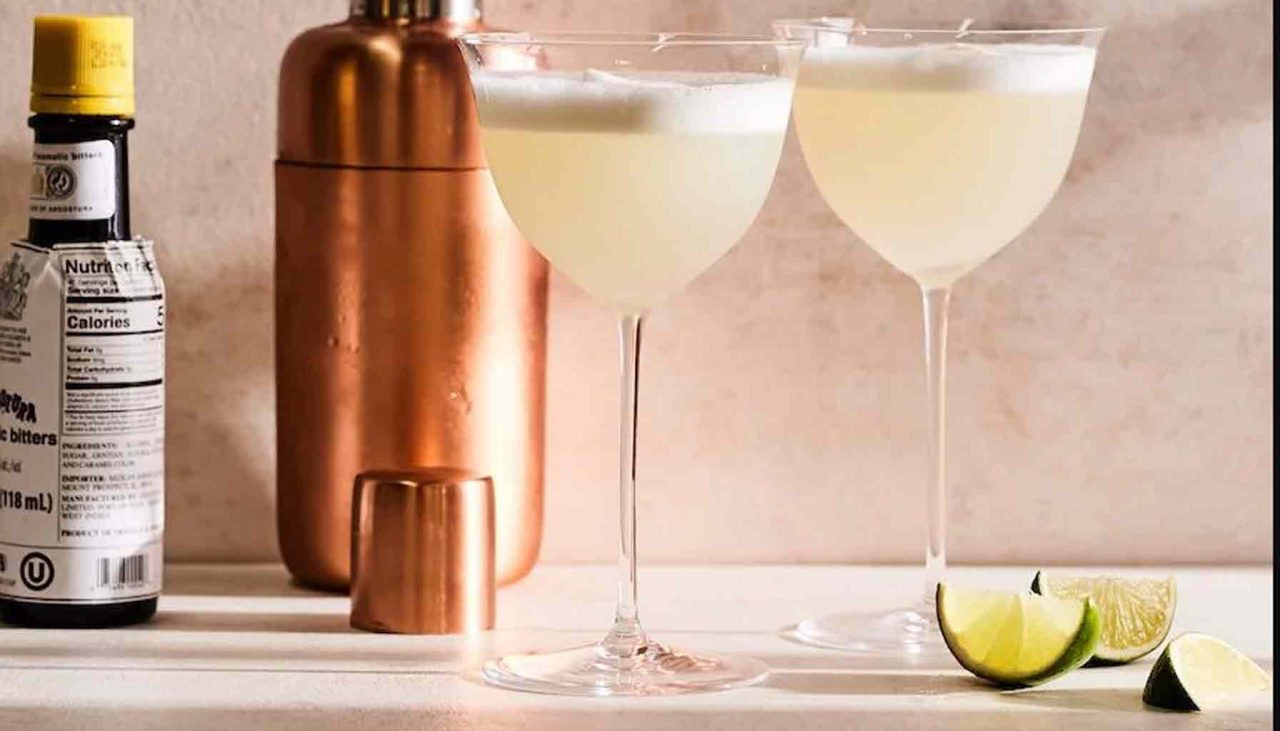 Egy bartender épp rázza a Pisco Sour koktélt egy shakerben, készen arra, hogy a tökéletesen habos ital egy pohárba kerüljön, Angostura bitters díszítéssel.